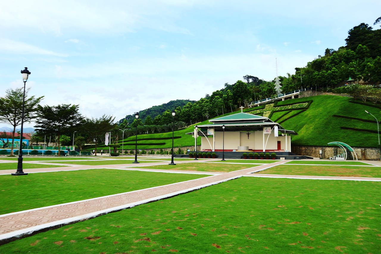 A tranquil outdoor chapel surrounded by a landscaped garden and vibrant green grass.
